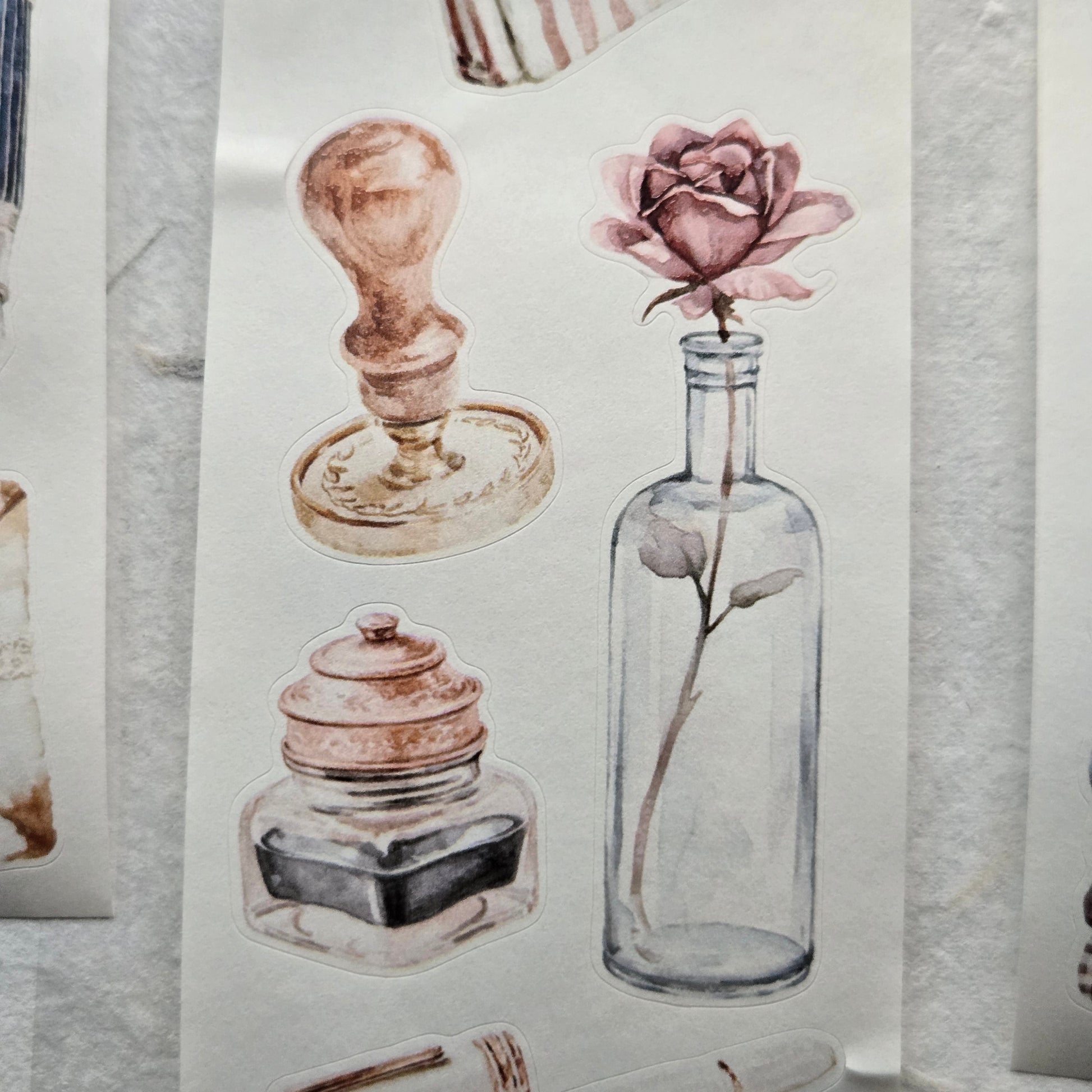 Decorative paper with illustrations of a rose in a bottle and candle holders on a marble surface.