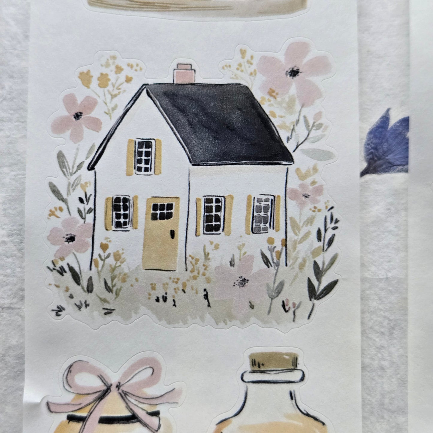 Decorative paper with a house illustration and floral elements on a textured surface.