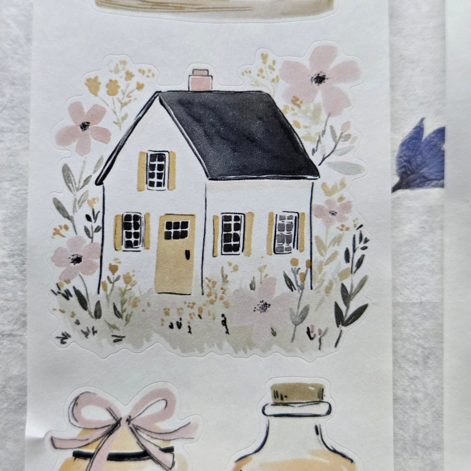 Decorative paper with a house illustration and floral elements on a textured surface.