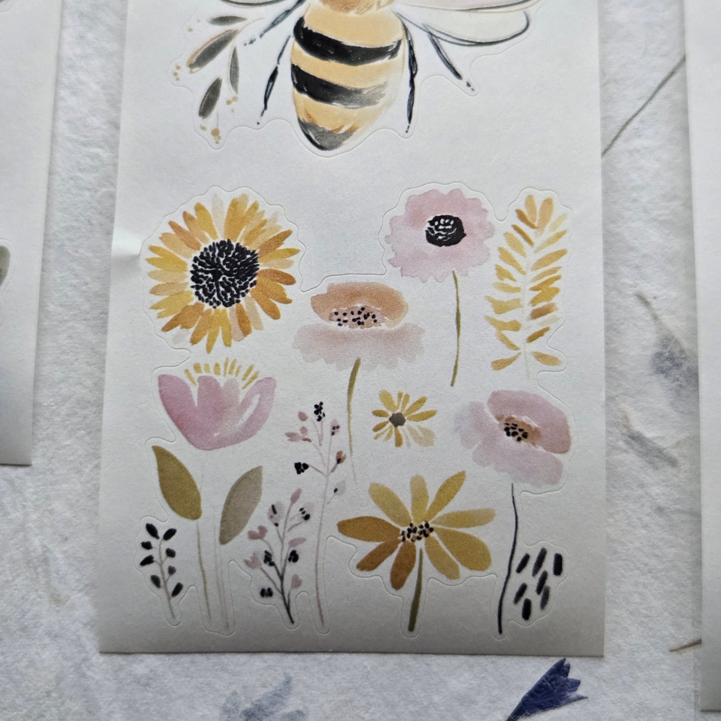 Sheet of floral and bee stickers on a textured white surface