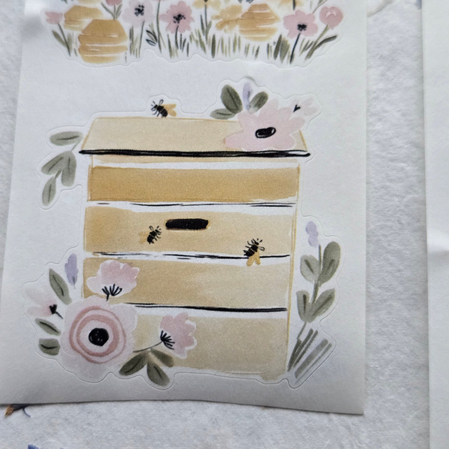 Decorative paper cutout with floral and bee designs on a textured white background