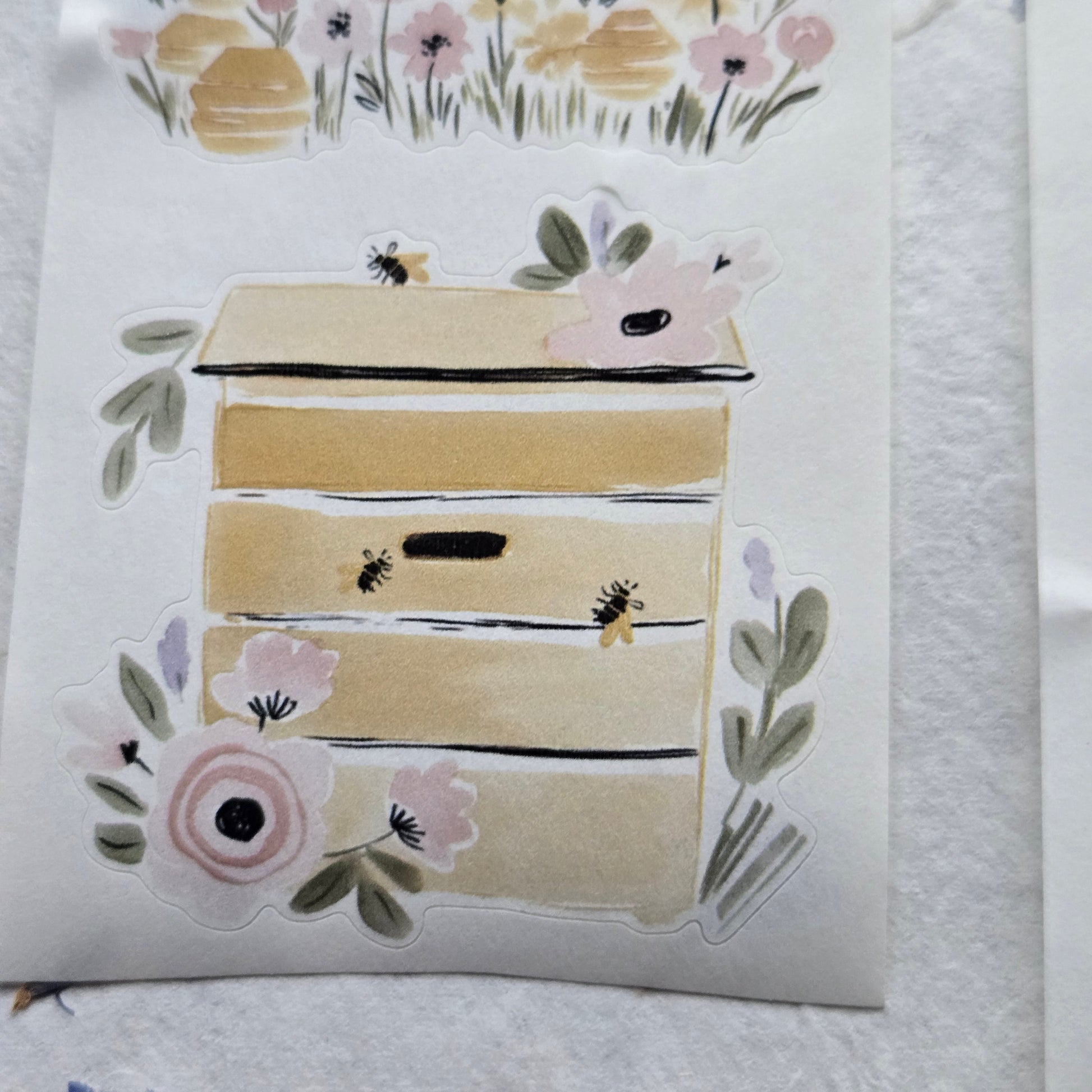 Decorative paper cutout with floral and bee designs on a textured white background