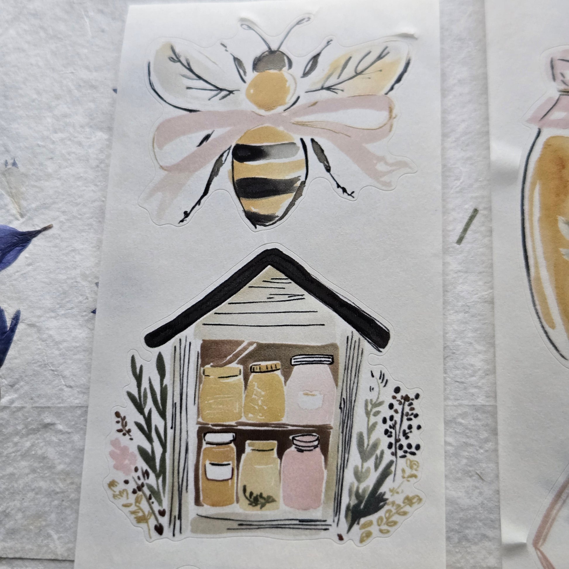 Sheet of paper with illustrations of a bee, a house, and other decorative elements on a textured white background.