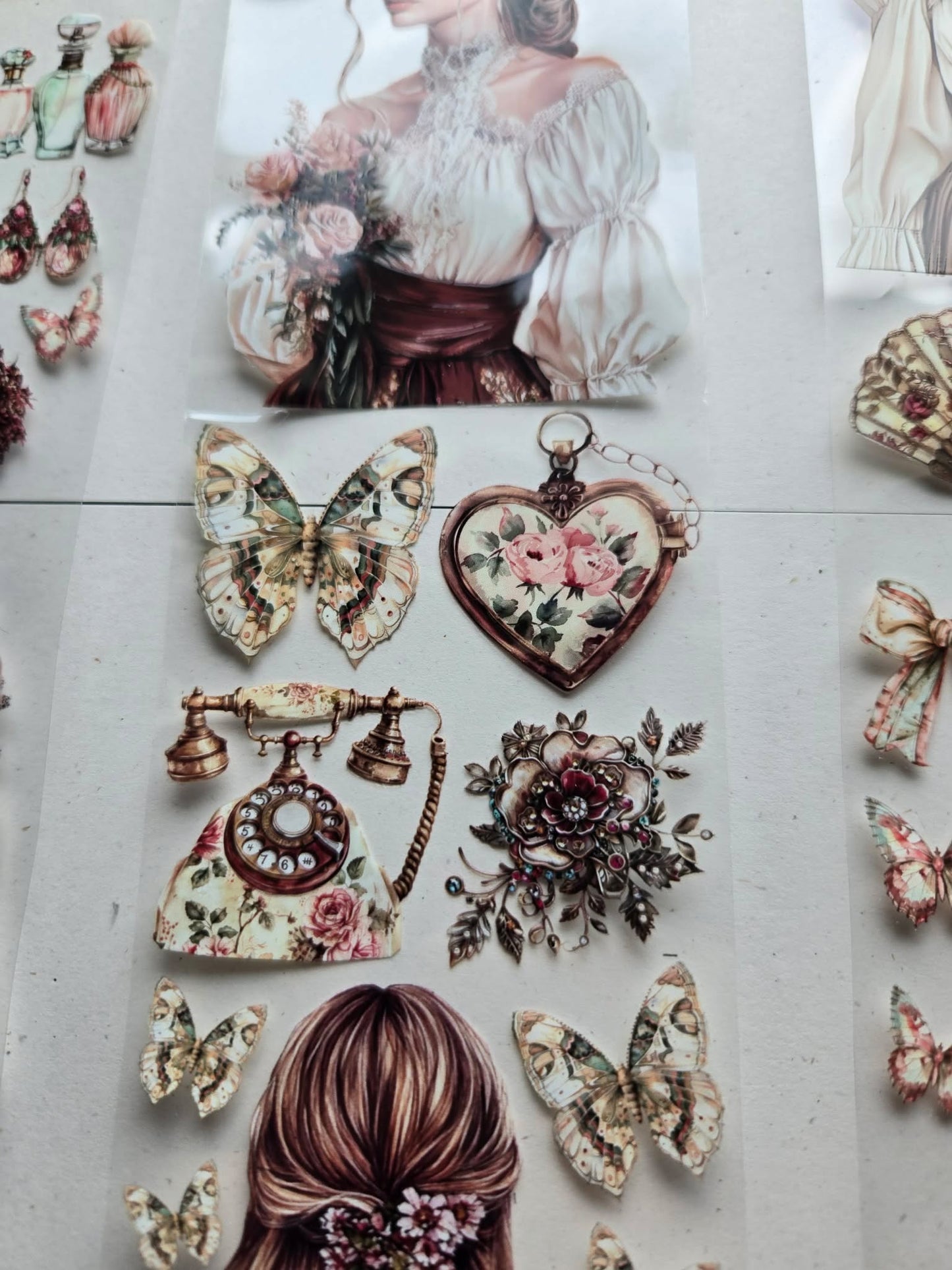 Vintage-style decorative elements including a woman's portrait, butterflies, and floral heart on a textured surface.