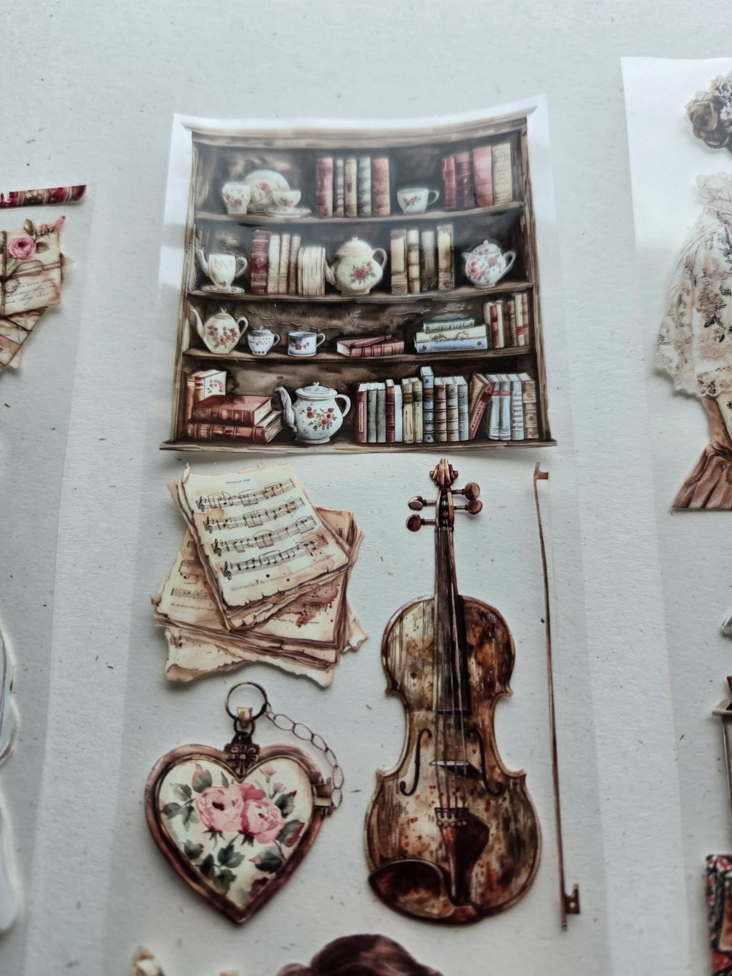 Vintage-themed stickers including a violin, books, teacups, and a heart-shaped keychain on a white background.